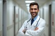 © Valentina Zaitseva - smiling male doctor in white professional clothes standing looking at camera with arms folded on chest, blurred white hospital corridor on background
