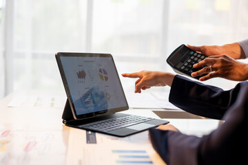 two people are working on a computer with a tablet and a calculator