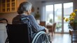 © Morning - An elderly woman in a wheelchair is sitting in a living room and looking out the window.