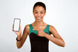 © Prostock-studio - Fit Black Girl Pointing Finger Showing Smartphone Blank Screen Recommending Fitness App Standing Over Yellow Background. Studio Shot, Mockup
