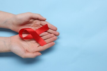 Canvas Print - Woman with red ribbon on light blue background, top view and space for text. HIV (AIDS) disease awareness