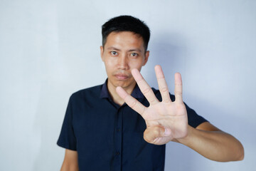 serious asian man giving four finger sign. white background