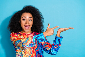 Sticker - Photo portrait of beautiful curly hair woman in trendy pullover holding hand empty space shopping season isolated on blue color background