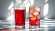 © deafebrisa - Two glasses of red drinks with ice on reflective surface