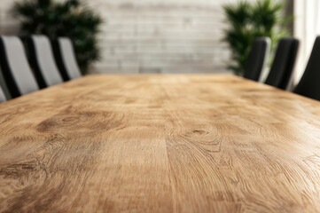 Aufkleber - Empty wooden table is providing copy space in a modern office with blurred chairs and plants in the background