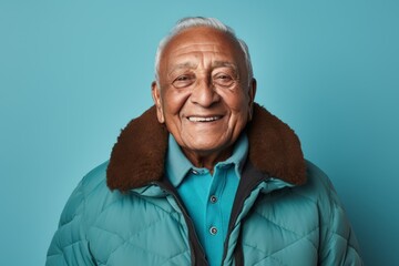 Poster - Portrait of a cheerful indian elderly man in his 90s donning a durable down jacket in front of soft teal background