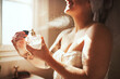 © Malambo/peopleimages.com - Woman, perfume spray and bathroom with relax, skincare and bottle for scent and fragrance at home. Calm, beauty product and body mist with cosmetics and morning routine with grooming, smile and towel