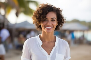 Wall Mural - Portrait of a jovial woman in her 30s wearing a simple cotton shirt while standing against bustling beach resort background