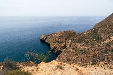 Wall Mural - Scenic view of a rocky coastline with clear blue ocean water under a cloudy sky
