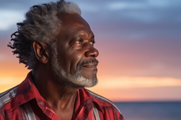 Canvas Print - Portrait of a glad afro-american man in his 70s wearing a comfy flannel shirt while standing against vibrant beach sunset background