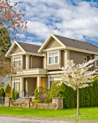 Two story stucco luxury house with nice spring blossom landscape in Vancouver, Canada