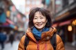 © Markus Schröder - Portrait of a blissful asian woman in her 60s dressed in a water-resistant gilet isolated in vibrant market street background