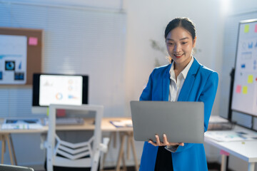 Confident young businesswoman in modern office, smiling while working on laptop. Professional, successful, using technology to communicate effectively