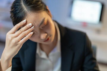 Stressed businesswoman in office touching head, working on laptop, struggling with pressure, deadlines, exhaustion of corporate life