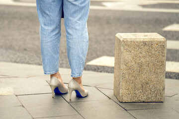 stylish contrast of casual jeans and elegant high-heeled shoes, embodying modern femininity as the girl stands confidently on the sidewalk, merging comfort with sophistication