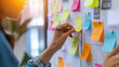 © Mirjana - Managers coordinating development strategies by arranging sticky notes on a board in a collaborative workspace during the daytime