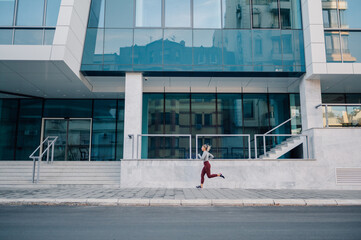 Wall Mural - Young sporty woman running in the city