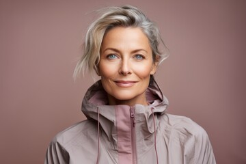 Canvas Print - Portrait of a tender woman in her 40s wearing a functional windbreaker on pastel or soft colors background