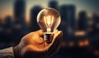 © S@photo - Hand Holding Light Bulb with City Skyline Background