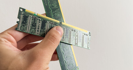 Man holding up a RAM module, or random access memory, in which all storage locations can be rapidly accessed in the same amount of time used by a computer operating system, on white