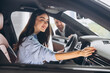 © anatoliycherkas - Friendly male manager showing young female customer cars. Beautiful smiling woman sitting inside vehicle in car. Bearded sales consultant working in car dealership.