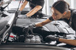 © anatoliycherkas - Trying to identify the source of the problem. Close-up shot of two mechanics man and woman working together at open hood on a car in an auto repair shop.