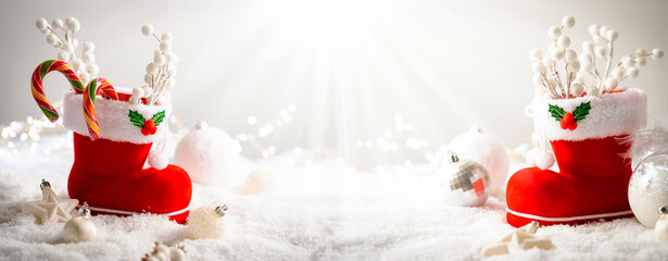 Wall Mural - christmas creative composition made with santa boots with sweets and gifts on snow background. minim