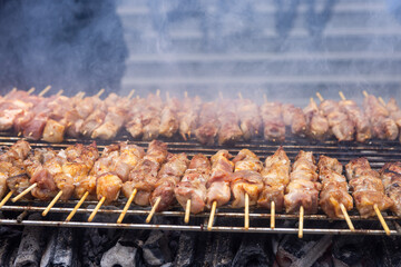 A grill filled with skewers of meat cooking