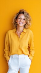 Wall Mural - A woman joyfully laughing at the camera, wearing a bright yellow blouse against a vibrant orange background in a studio setting