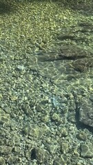 Poster - Sea water calm transparent surface with pebbles at the bottom, vertical video.