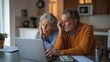 © Bonsales - Concerned elderly couple sitting at a kitchen table, anxiously viewing financial information on a laptop screen with calculator.