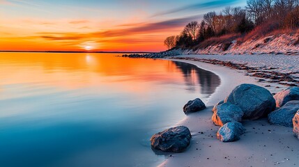 Wall Mural - a quiet secluded beach with calm waters reflecting the colors of a vibrant sunset rocks lining the s