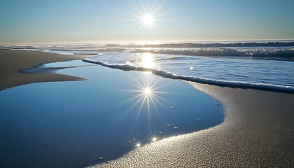 Wall Mural - Sunlight glistening off the wet sand as the waves retreat leaving behind small pools of water reflecting the sky