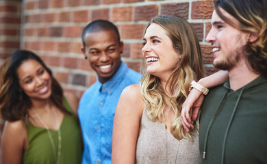 Happy, bonding and group of friends by brick wall in city for exploring, vacation or adventure. Laughing, hanging out and young people in conversation with diversity together in town on holiday.