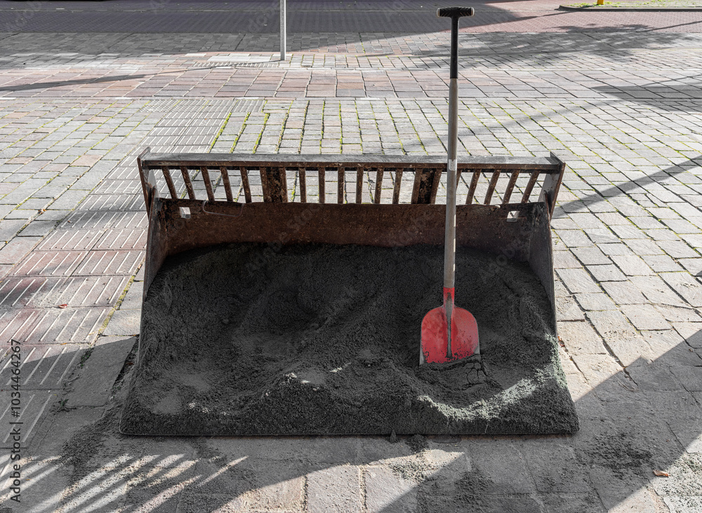 steel shovel bucket filled with sand in which a shovel is inserted