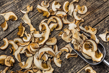 Wall Mural - Dried porcini mushrooms. Sliced boletus in scoop on wooden table. Top view.