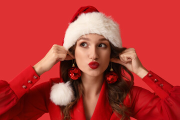 Young woman in Santa hat with Christmas balls on red background