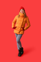 Sticker - Beautiful young happy woman in warm winter clothes on red background