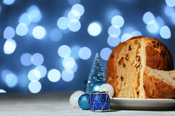 Wall Mural - Plate with cut Panettone and Christmas balls on blue blurred background