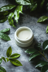 Wall Mural - A white jar of moisturizer with creamy texture is placed on a polished grey surface, next to bright green leaves. The simplicity of the grey background highlights the natural elements, promoting a