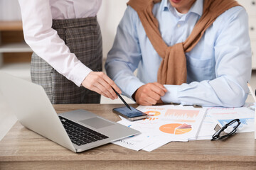 Male economist and colleague working with diagrams on mobile phone in office, closeup