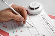 © Pixel-Shot - Man with smoke detector drawing evacuation plan on grey background, closeup
