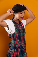 Portrait of beautiful brunette teenage girl wearing black beret with braids in her hair, holding the beret.