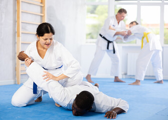 Wall Mural - Man and woman practicing judo together on sports mats in gym