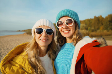 Wall Mural - Happy young two women friends taking selfie with phone on beach, smiling girlfriends having fun