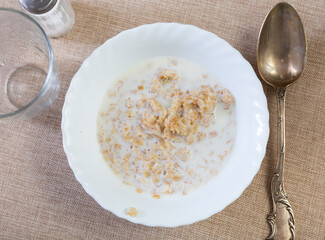 There is plate of oatmeal on checkered tablecloth. Homemade healthy food for children and adults. Nutritious and dietary product