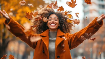 Stylish young woman in a trendy autumn coat throws colorful leaves in the air while smiling in a city park on a cool morning