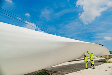 two engineers inspect a massive wind turbine blade at a construction site. the image showcases the s