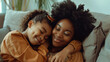 © MariКа - mothers day beautiful black african american mother and daughter cuddle at home on sofa