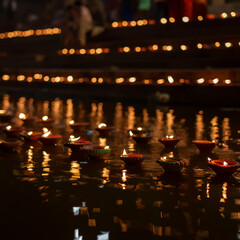 Diyas floating and arranged along water steps, creating a reflective and warm ambiance during the evening of Chhath Puja